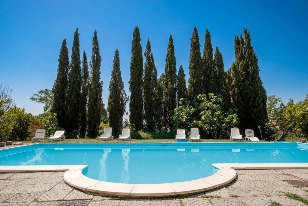 a swimming pool in front of a row of trees at Casale I Cascetti in Piancastagnaio