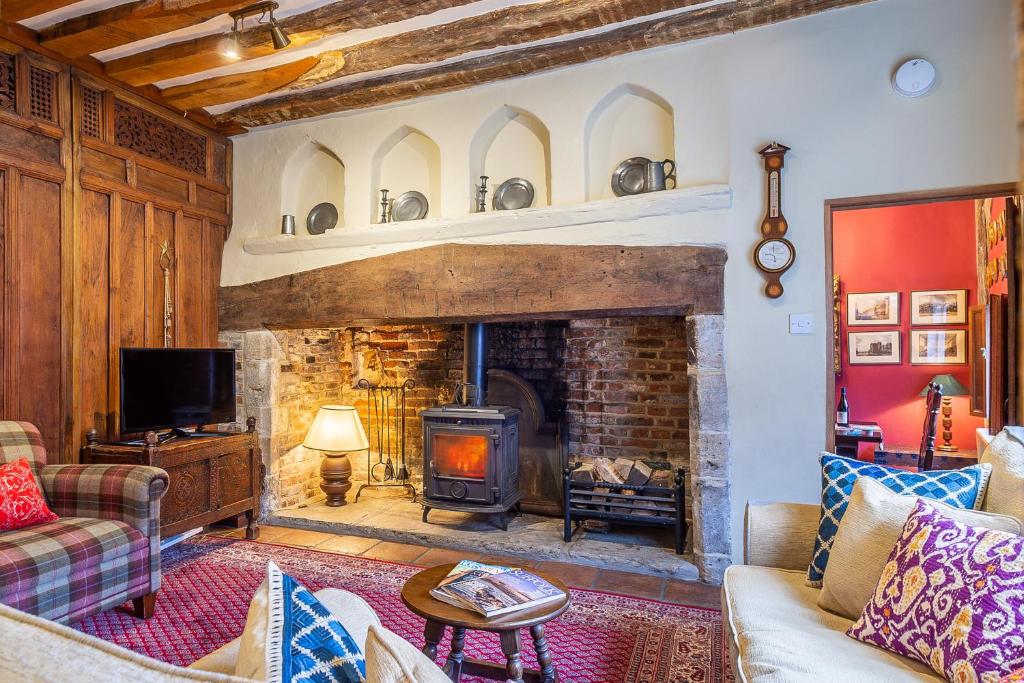 a living room with a stone fireplace with a stove at Extraordinary 15th Century timber framed cottage in famous Medieval village - The Tryst in Lavenham