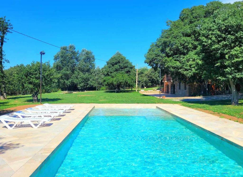 a swimming pool with white lounge chairs and trees at Recientemente restaurada ideal para grupos in Cabanellas