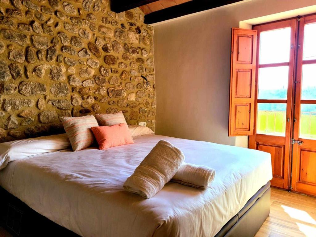 a bed in a room with a stone wall at Recientemente restaurada, ideal para grupos! in Cabanellas