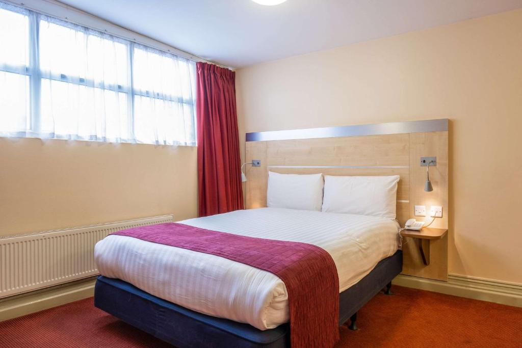 a bedroom with a large bed with a large window at Comfort Inn Edgware Road W2 in London