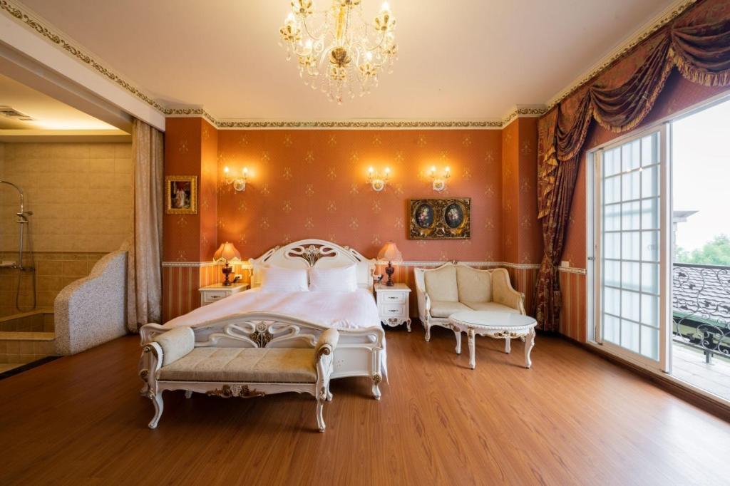 a bedroom with a bed and a tub and a chandelier at Cingjing Florence Resort Villa in Ren&#39;ai