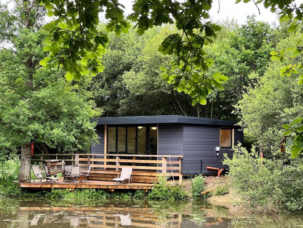 una pequeña casa en un muelle en un río en Cackle hill lakes, Kingfisher Lodge, en Biddenden