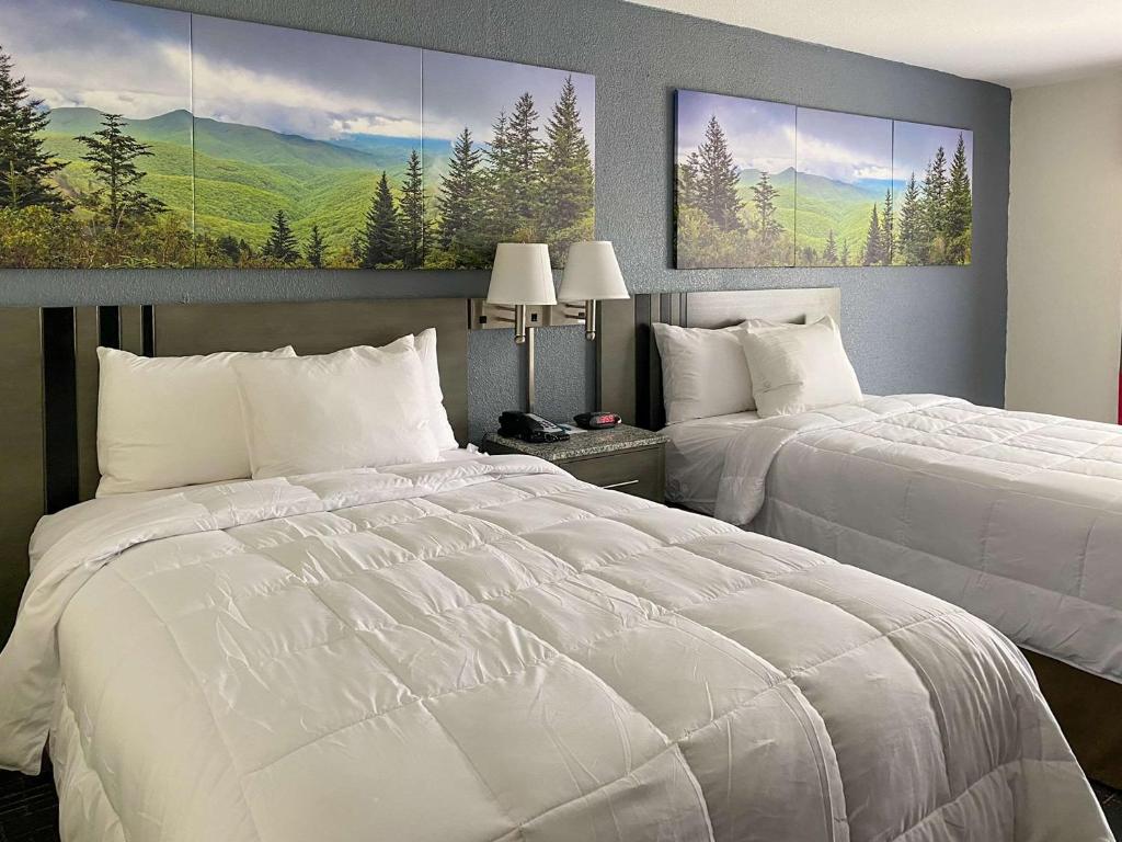 two beds in a hotel room with white sheets at Clarion Pointe - Greensboro Coliseum Area in Greensboro