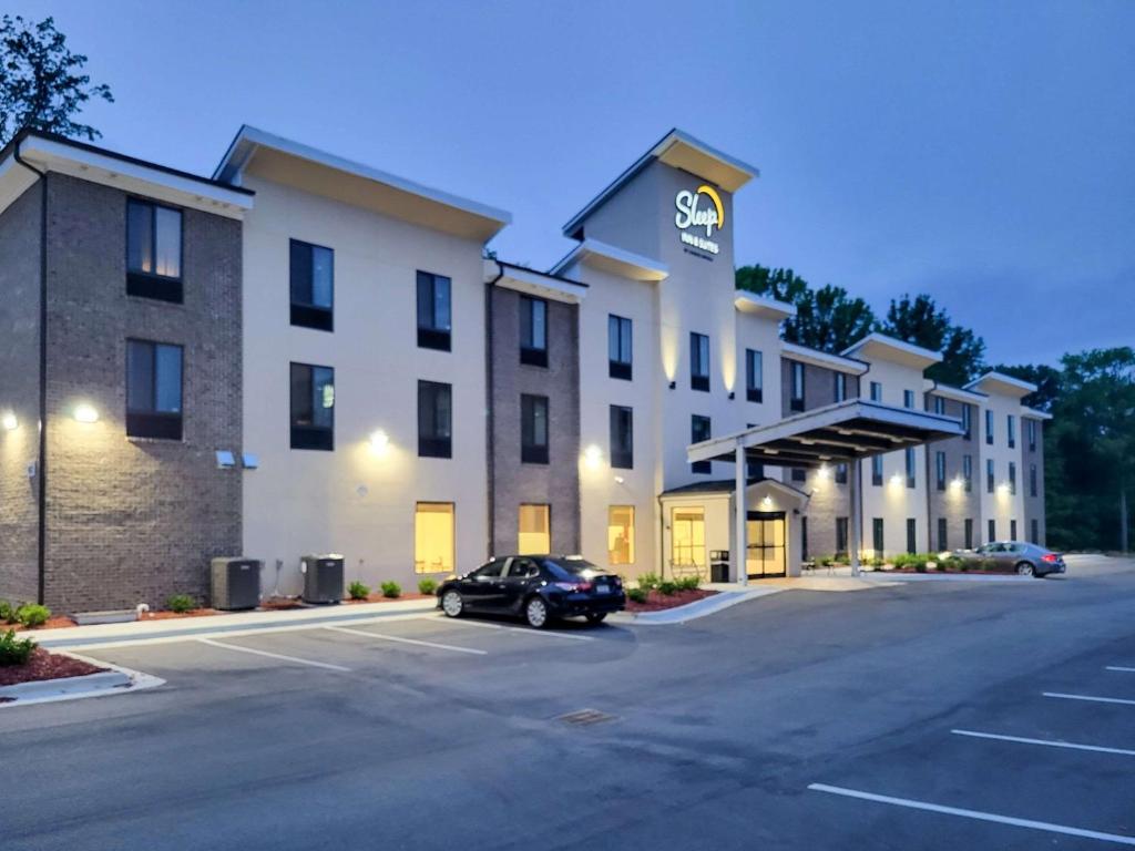 a hotel with a car parked in a parking lot at Sleep Inn & Suites - Coliseum Area in Greensboro