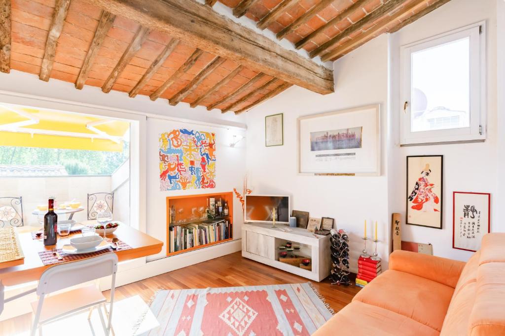 a living room with a couch and a table at Piazza dei Cavalieri Orange Attic Apartment in Pisa