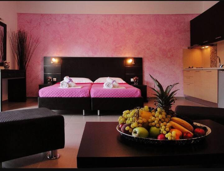 a room with a bed and a bowl of fruit on a table at Dafni studios in Parga
