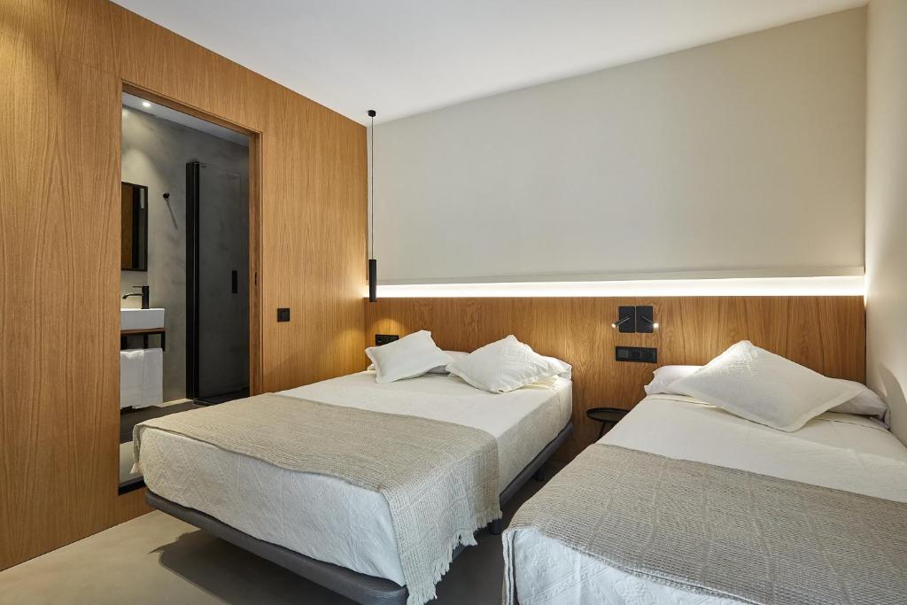 two beds in a room with wooden walls at Ella Hostel Ramblas in Barcelona