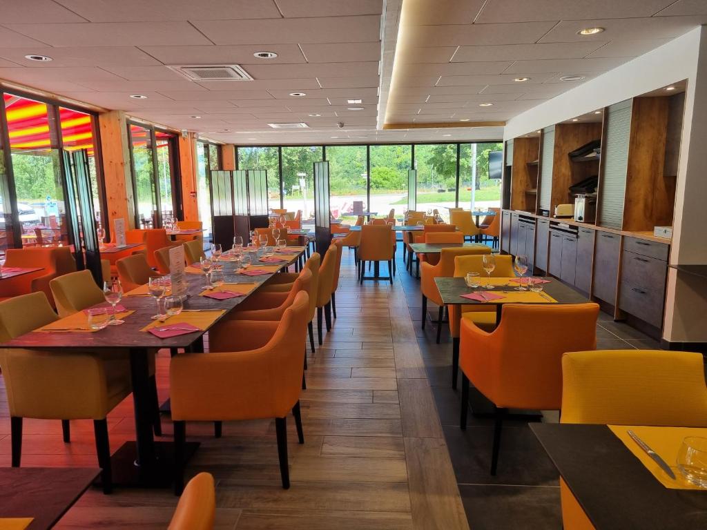 - une salle à manger avec des tables, des chaises et des fenêtres dans l'établissement Akena Molinges - La Brocatelle, à Saint-Claude