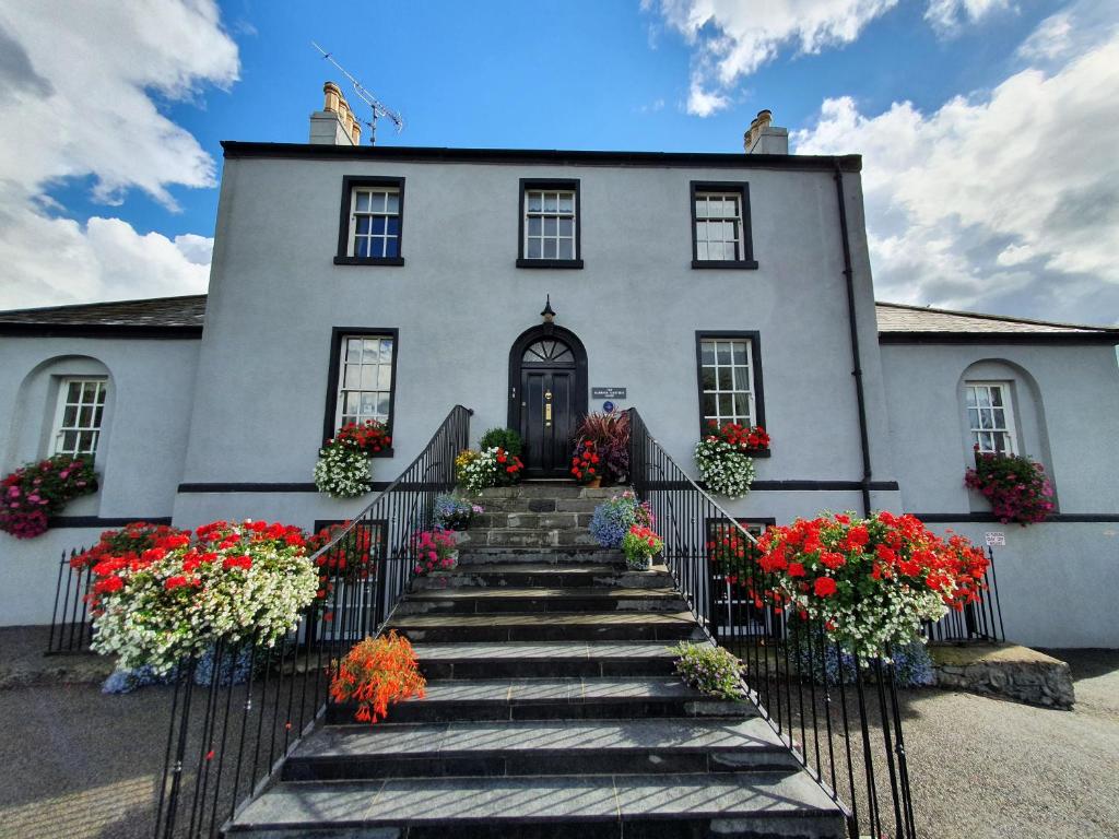 a white house with flowers on the stairs at The Harbour Masters House in Banagher