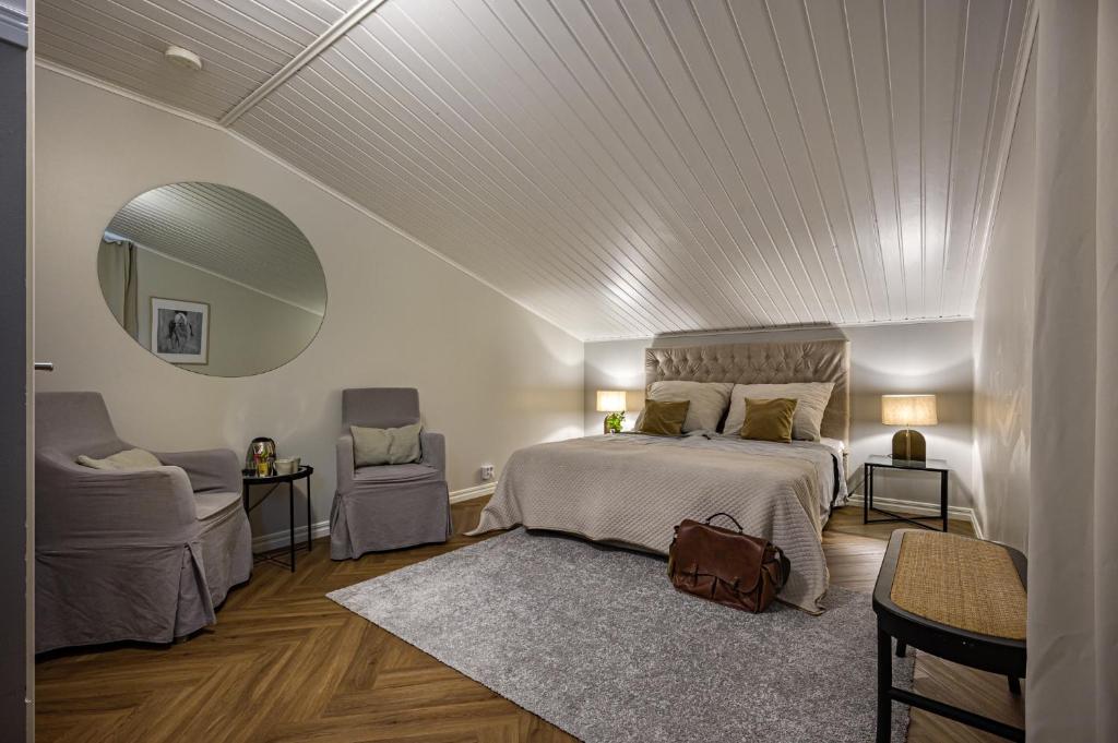 een slaapkamer met een bed, een spiegel en een stoel bij Tukkilan Tila in Porvoo