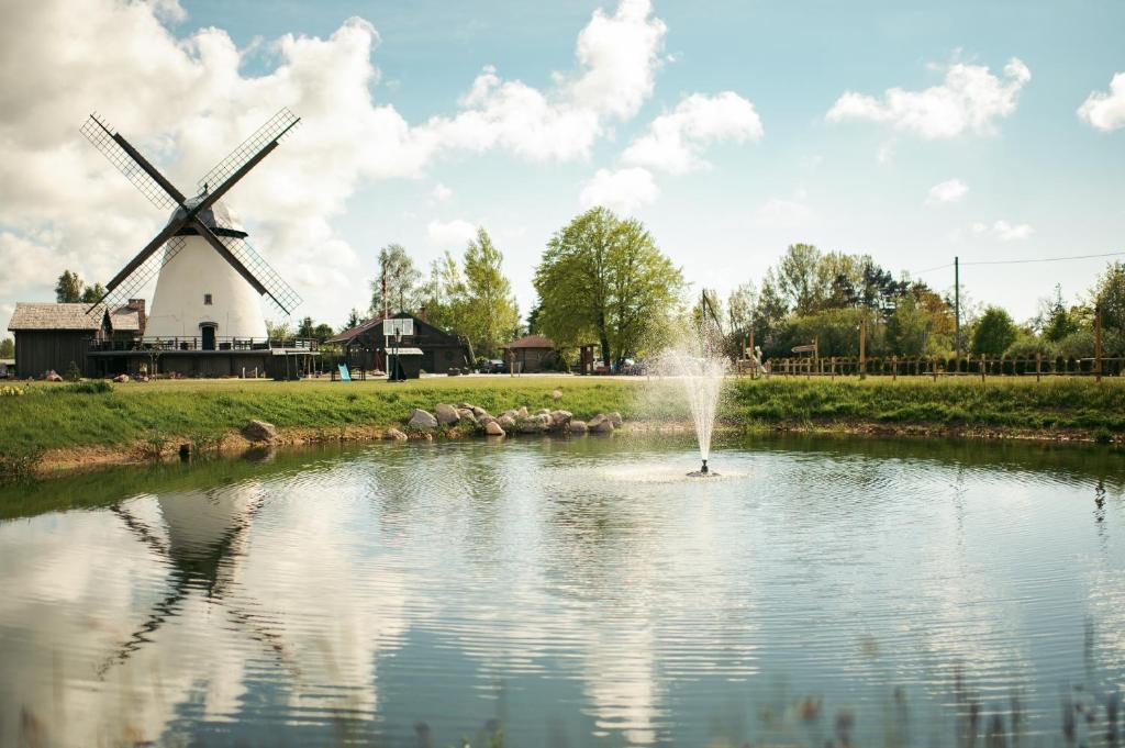 a fountain in a pond in front of a windmill at Apartamenti Vējdzirnavas in Ventspils