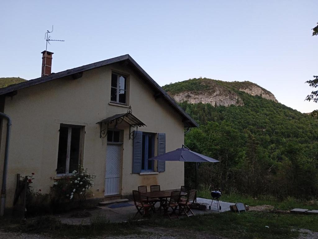 une maison avec une table et un parasol dans l'établissement gite la cordée, à Lavans-lès-Saint-Claude