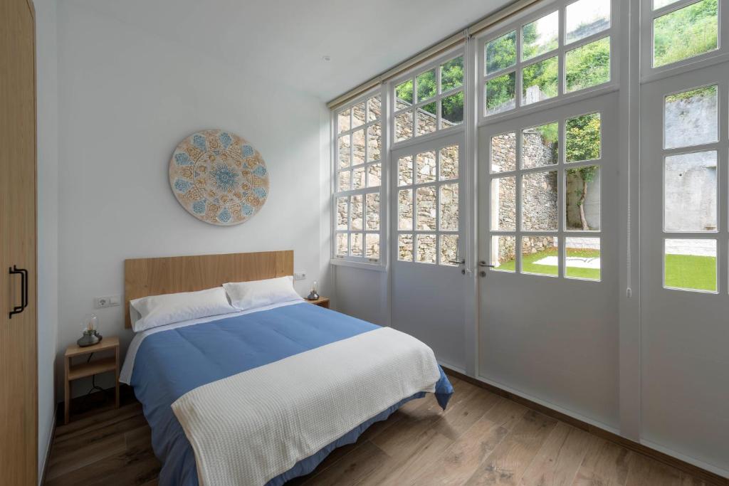 Schlafzimmer mit einem Bett und großen Fenstern in der Unterkunft Apartamentos Bestarruza in Mugardos