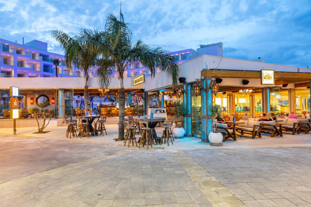 a resort with tables and chairs and palm trees at Limanaki Beach Hotel & Suites in Ayia Napa