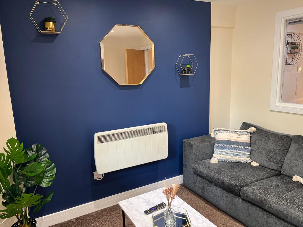 a living room with a couch and a blue wall at Elite 60 Stays in Newcastle upon Tyne