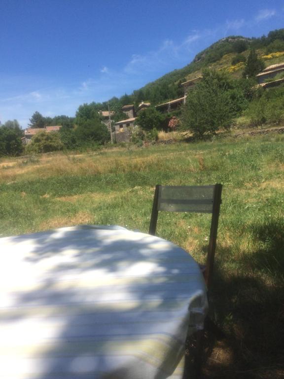 uma cadeira sentada ao lado de uma mesa num campo em L’Oiseau rêveur em Darbres