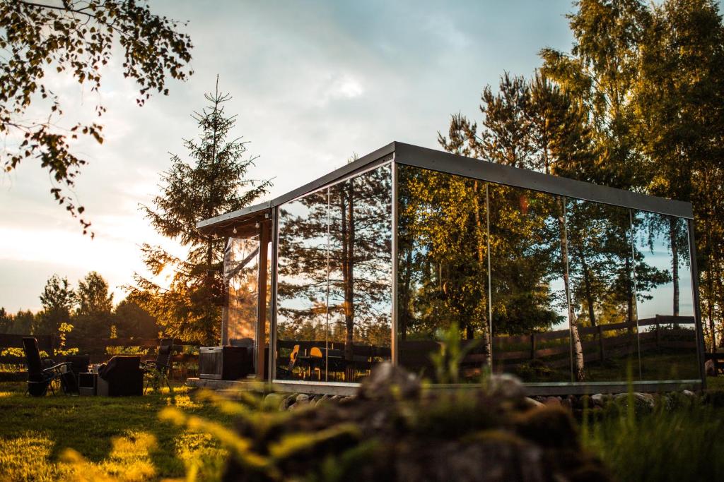 a glass house in the middle of a field at Mirror house in Tīnūži