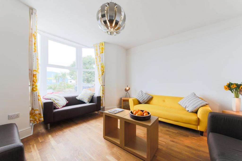 a living room with a yellow couch and a table at Sea View, Newquay Spacious house in Newquay