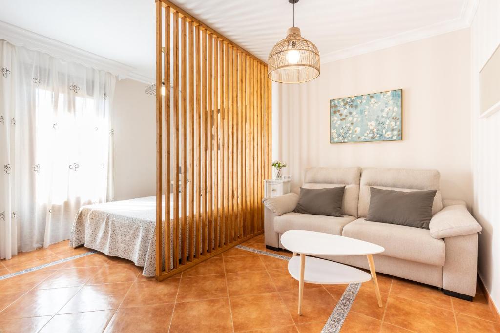 salon z kanapą i łóżkiem w obiekcie Casa Angelita Caminito del Rey, Dúplex con terraza en el centro de Andalucía w mieście Valle de Abdalagís