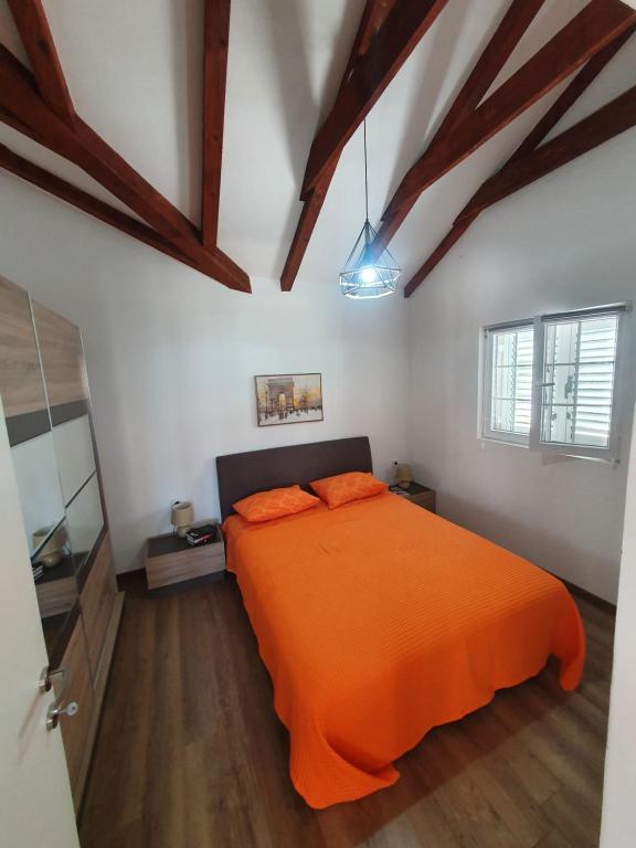 een oranje bed in een witte kamer met houten vloeren bij Villa RADA in Igalo