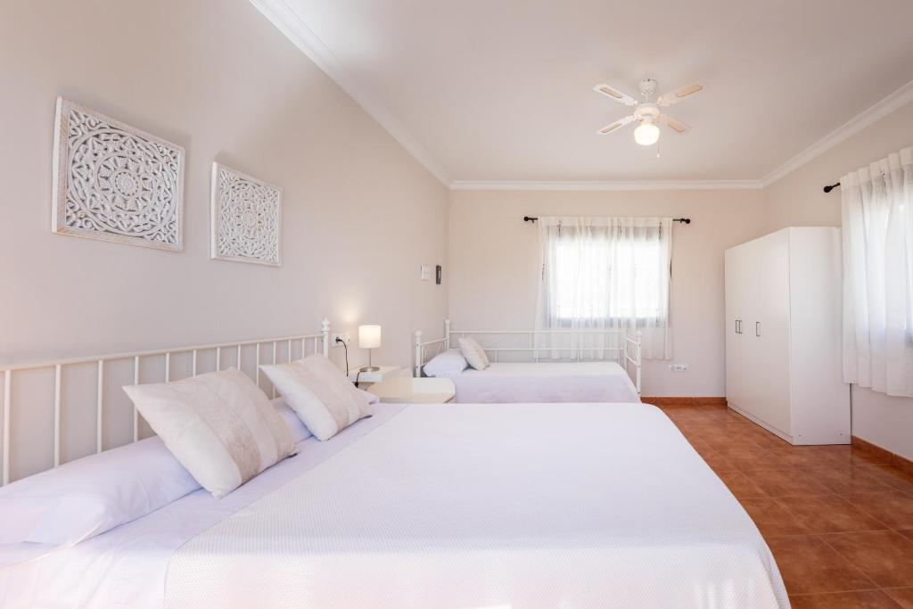 Biała sypialnia z 2 łóżkami i wentylatorem sufitowym w obiekcie Casa Angelita Caminito del Rey, Dúplex con terraza en el centro de Andalucía w mieście Valle de Abdalagís