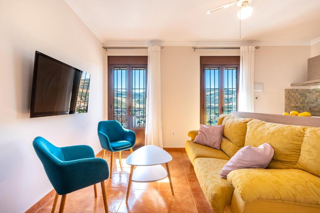 salon z żółtą kanapą i niebieskimi krzesłami w obiekcie Casa Angelita Caminito del Rey, Dúplex con terraza en el centro de Andalucía w mieście Valle de Abdalagís