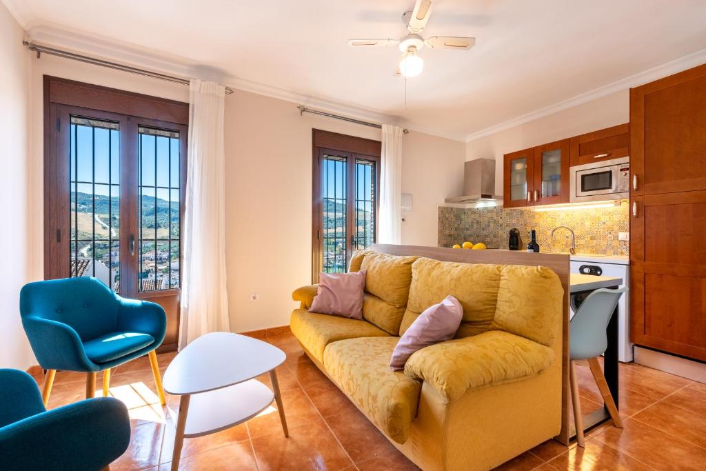 salon z żółtą kanapą i kuchnią w obiekcie Casa Angelita Caminito del Rey, Dúplex con terraza en el centro de Andalucía w mieście Valle de Abdalagís