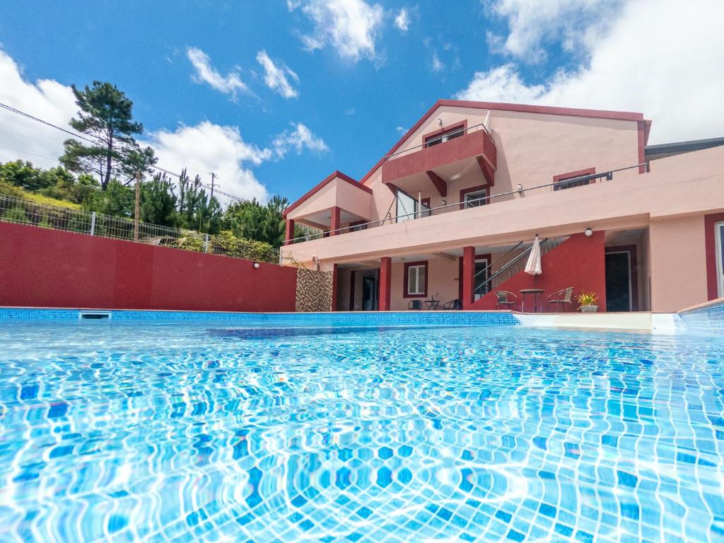 a swimming pool in front of a house at 2 bedrooms apartement with shared pool furnished terrace and wifi at Prazeres 5 km away from the beach in Campanário