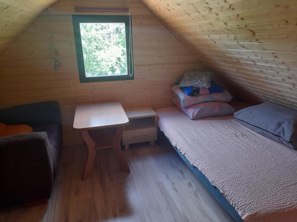 una habitación con una cama y una mesa en una cabaña en Domek na Skarpie, en Sztutowo
