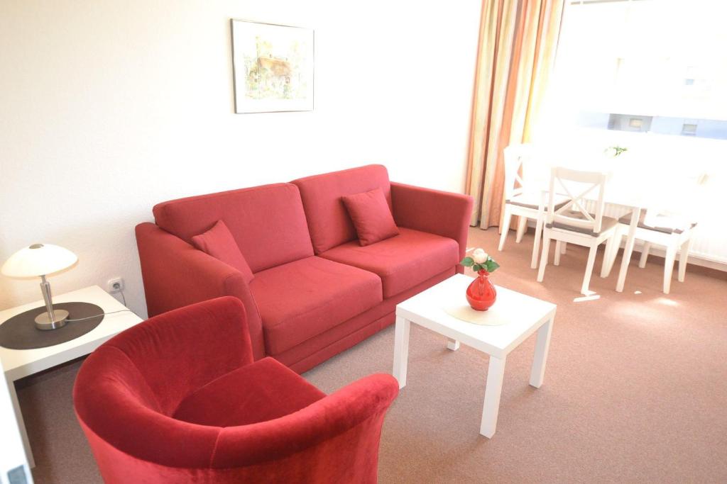 uma sala de estar com um sofá vermelho e cadeiras em Appartement-84 em Westerland