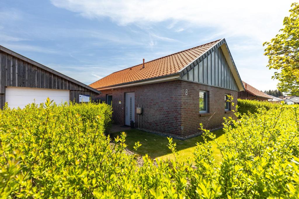 ein Backsteinhaus mit einem orangenen Dach und einem Hof in der Unterkunft Ferienhaus Südheide in Hermannsburg