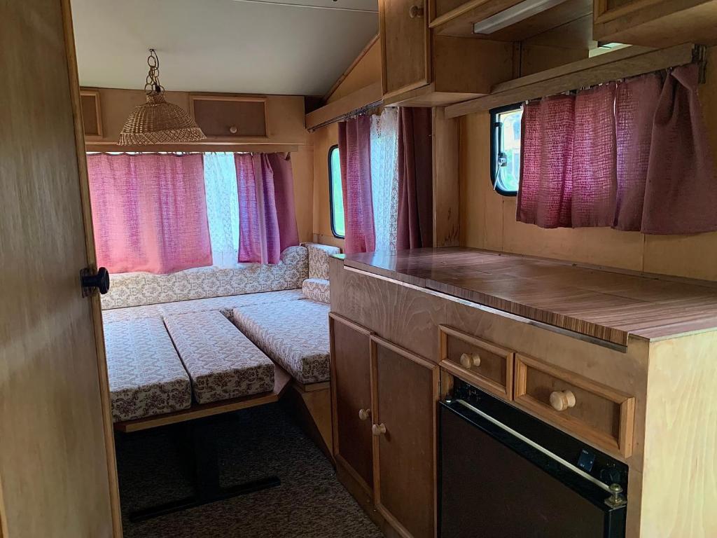 uma pequena cozinha com cortinas cor-de-rosa num trailer em Ubytování v karavanu em Bžany
