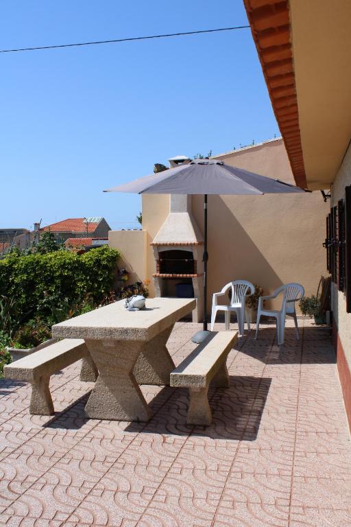 een picknicktafel en banken op een patio met een parasol bij Casa do Facho in Vila Chã