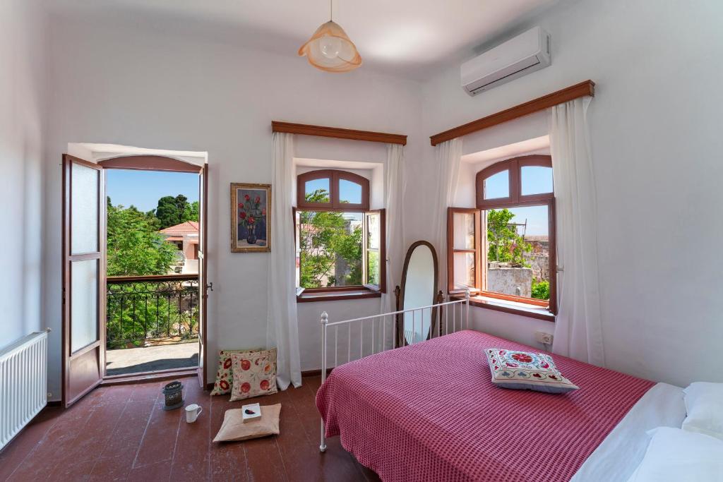 um quarto com uma cama com um cobertor vermelho e janelas em Traditional 3 bedroom house in the Old Town in Ilha de Rhodes
