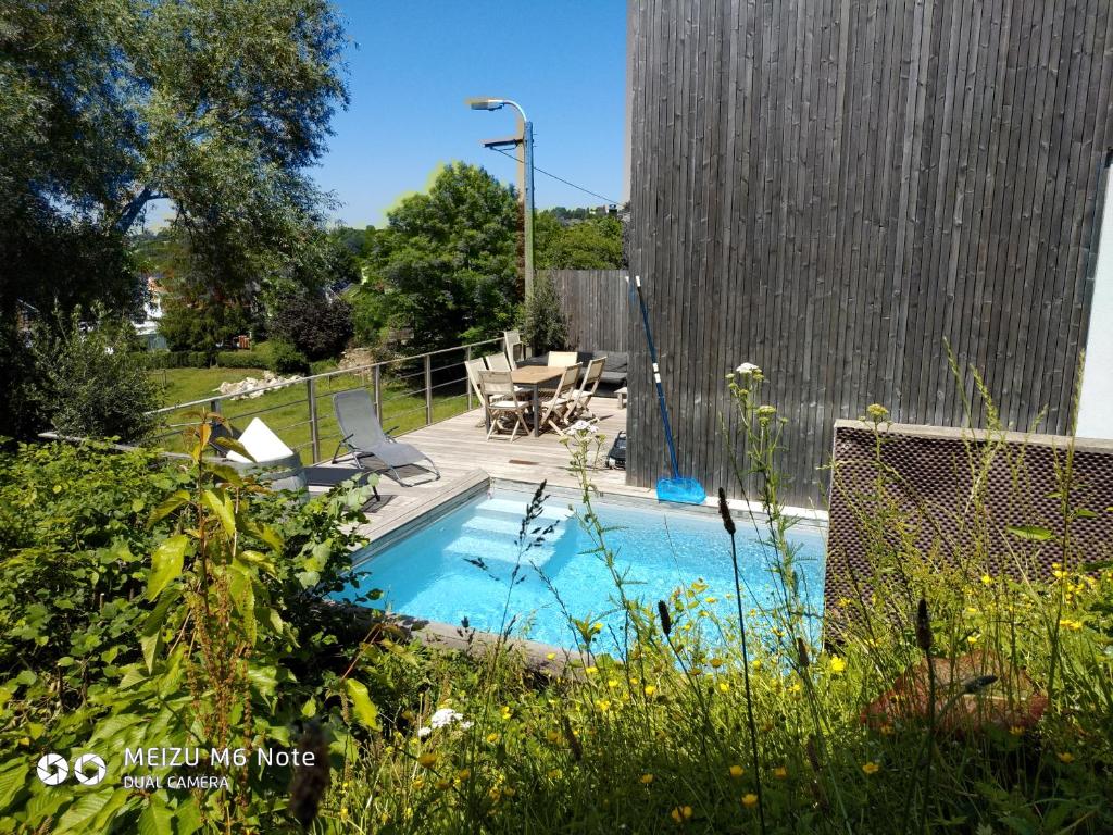 a swimming pool with a table and chairs in a yard at Maison à la porte des Ardennes in Verviers