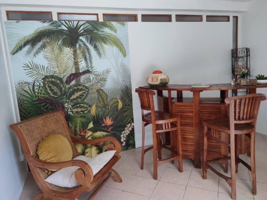 a room with a table and chairs and a palm tree mural at Entre Terre & Mer (Sainte rose)974 in Sainte-Rose