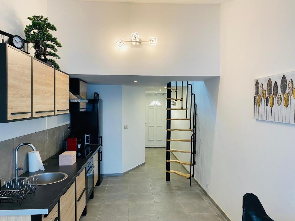 uma cozinha com um lavatório e uma escada num quarto em Douceur du sud em Vitrolles