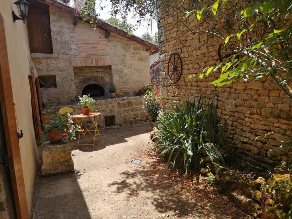een patio met een tafel en een bakstenen gebouw bij Cosy private cottage in Condac