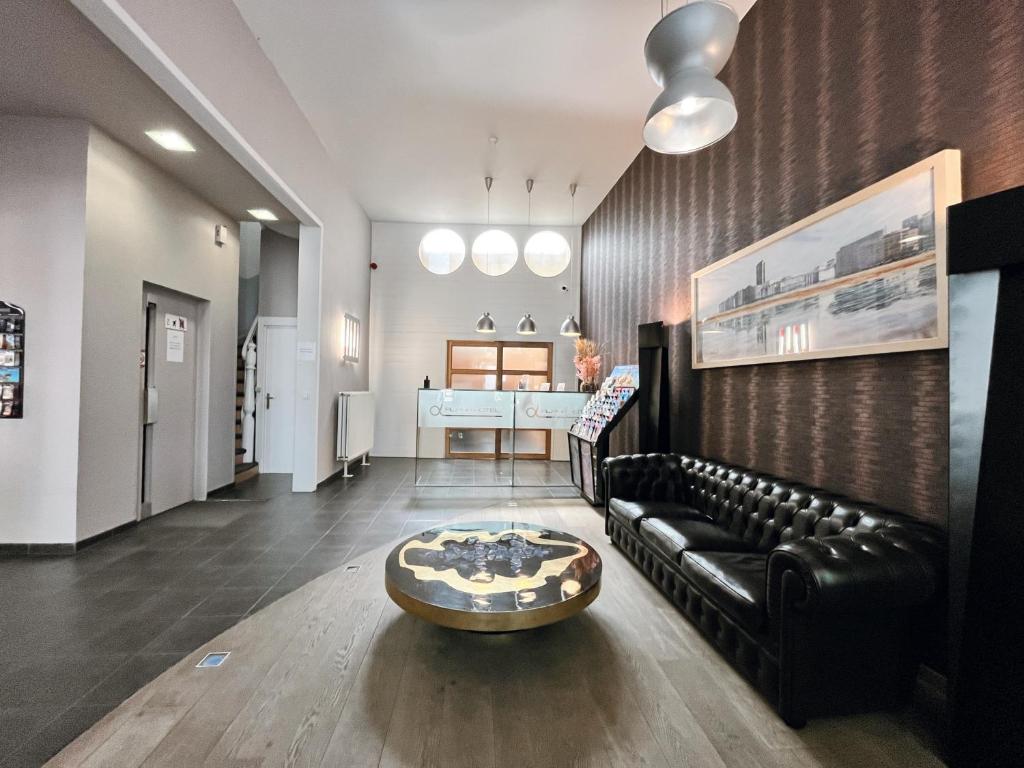 uma sala de estar com um sofá de couro preto e uma mesa em Alpha Hotel em Oostende