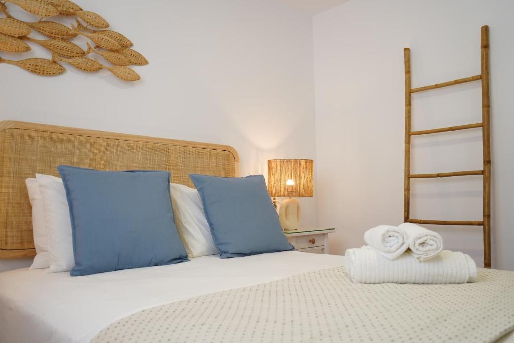 a bed with blue pillows and towels on it at Apartamento La Barca in El Rompido