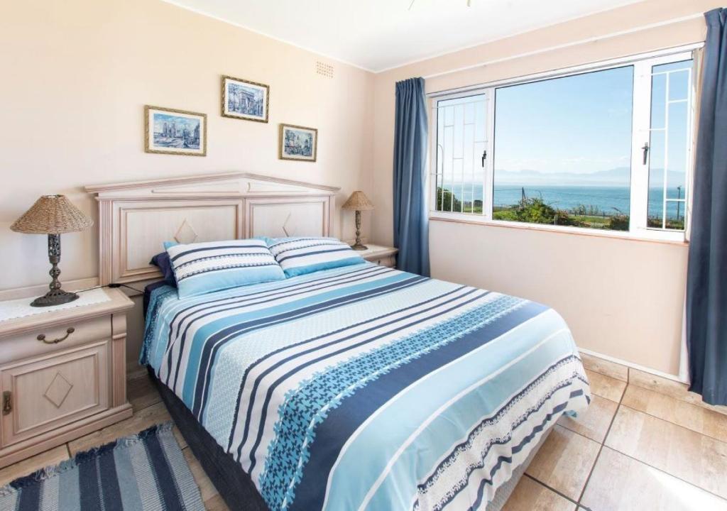 a bedroom with a bed and a large window at 82 De Bakke Terrace in Mossel Bay