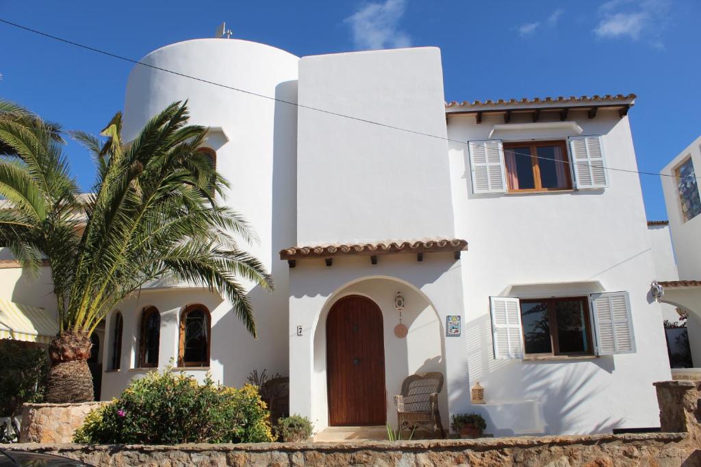 a white house with a palm tree in front of it at Casa Caliente in Cala Santanyi