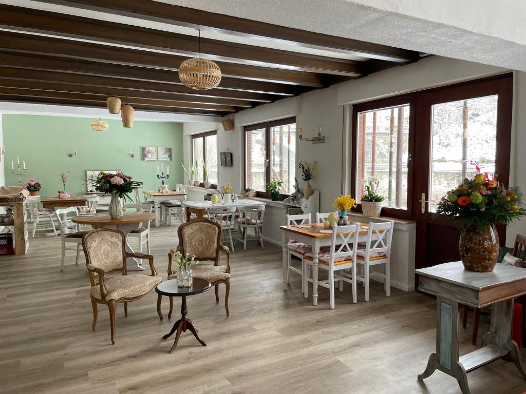 un comedor con mesas, sillas y ventanas en Bed&Breakfast Eifelpension Brückenschenke en Fuchshofen