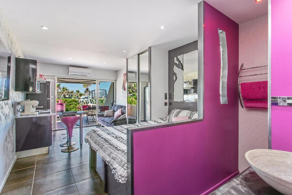 Cette chambre est dotée d'un mur violet avec un miroir. dans l'établissement Palmeraie beach Heliopolis Naturiste, au Cap d'Agde