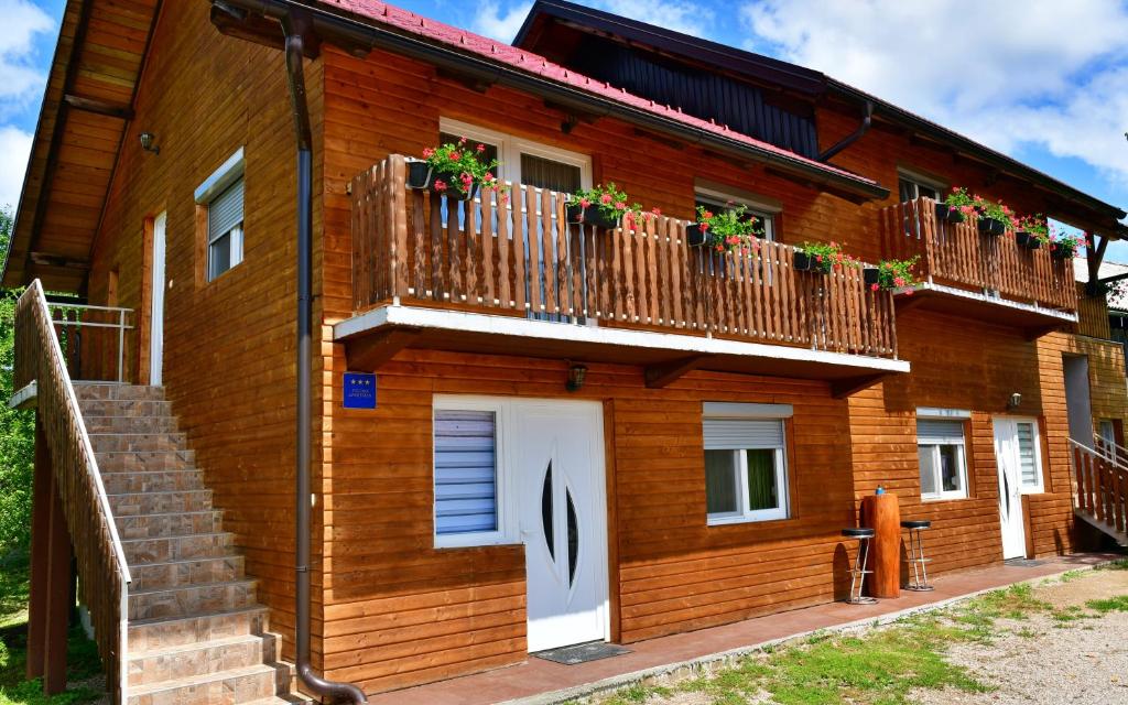 a wooden house with a balcony with flowers on it at Apartments Laura in Rakovica