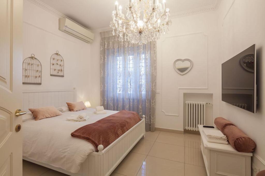 een witte slaapkamer met een bed en een kroonluchter bij Clara's Home in Rome