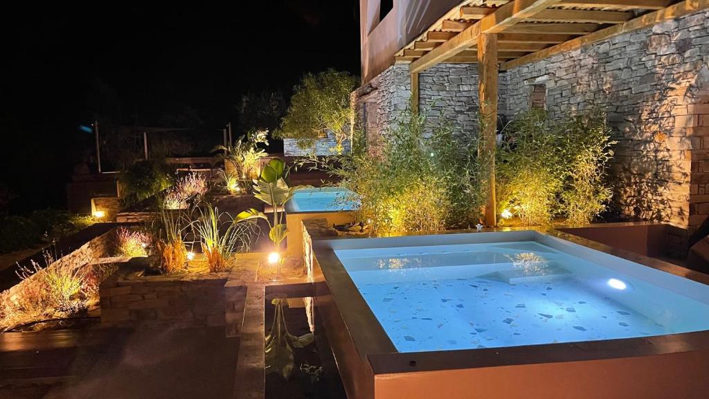 a hot tub in the middle of a garden at night at Gianemma Luxury Apartments in Mylopotas
