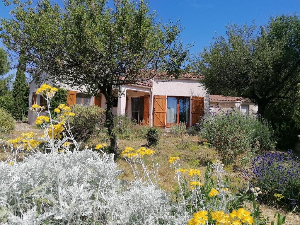 a house in the middle of a garden with flowers at Gîte Les Romarins in Saint-Jean-de-Minervois