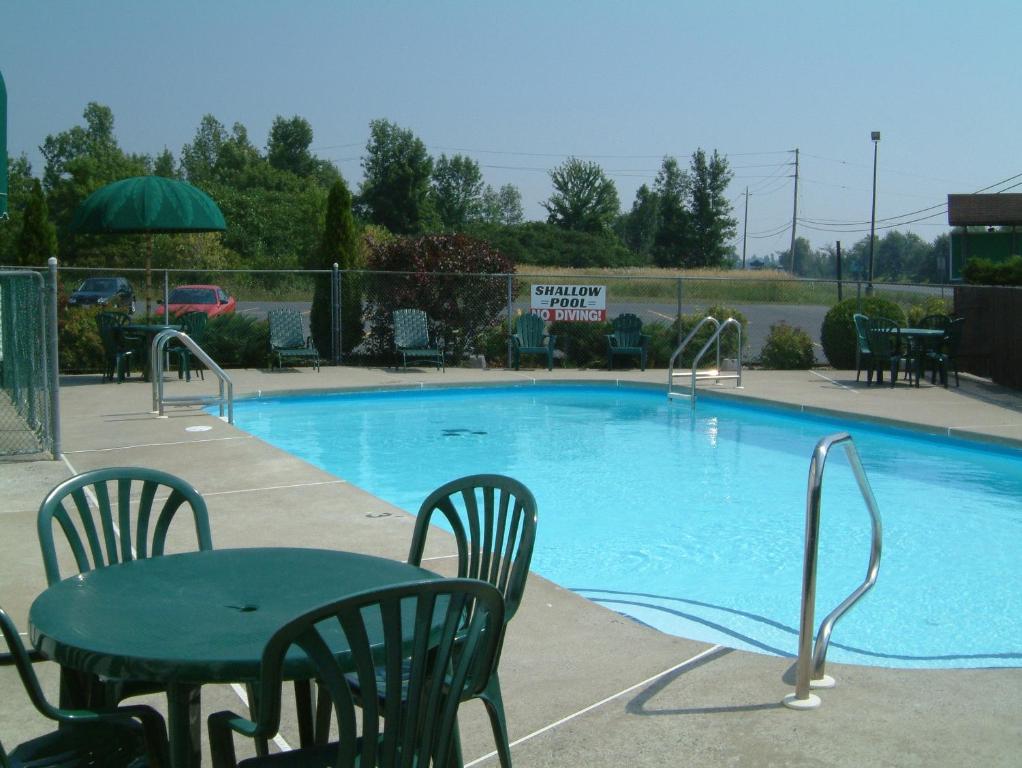 una piscina con mesa y sillas junto a ella en McIntosh Country Inn & Conference Centre, en Morrisburg